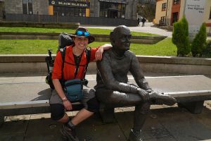 Walker sitting on bench next to statue